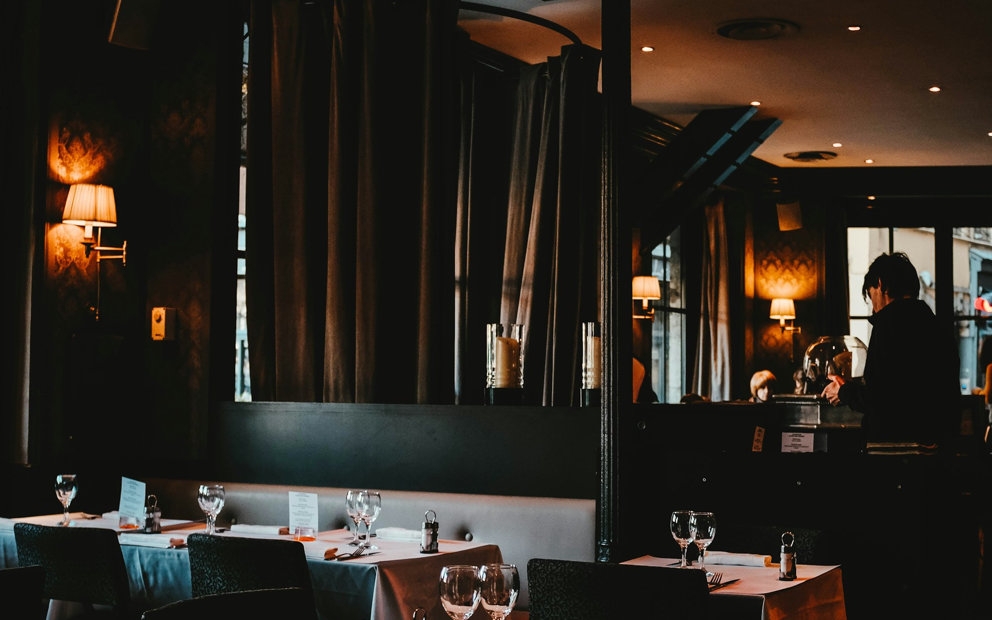 Warmly lit dining room with wall lamps and set tables
